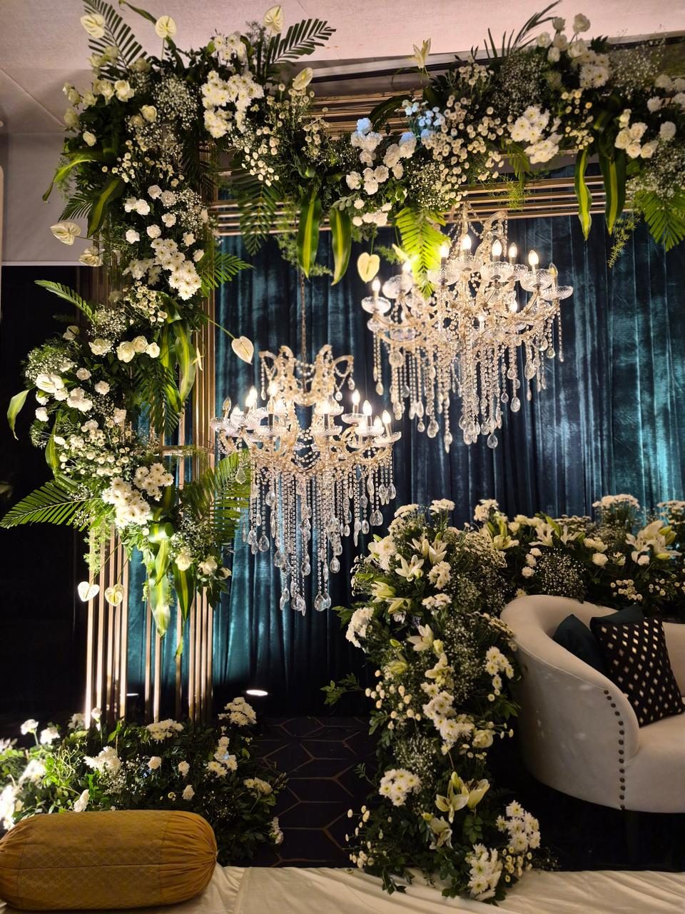 White floral arch with teal velvet curtain and crystal chandeliers