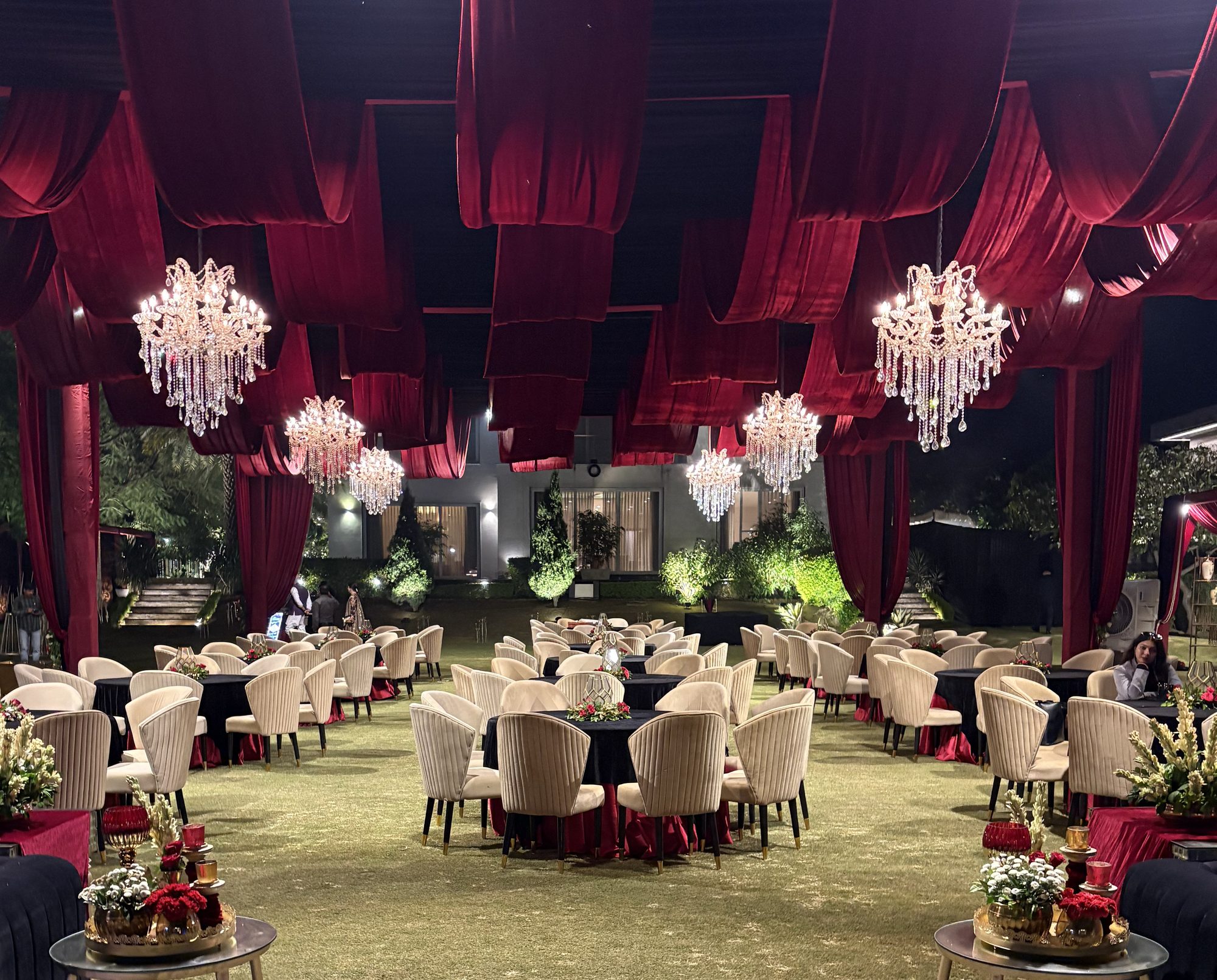 Maroon draped reception seating with crystal chandeliers