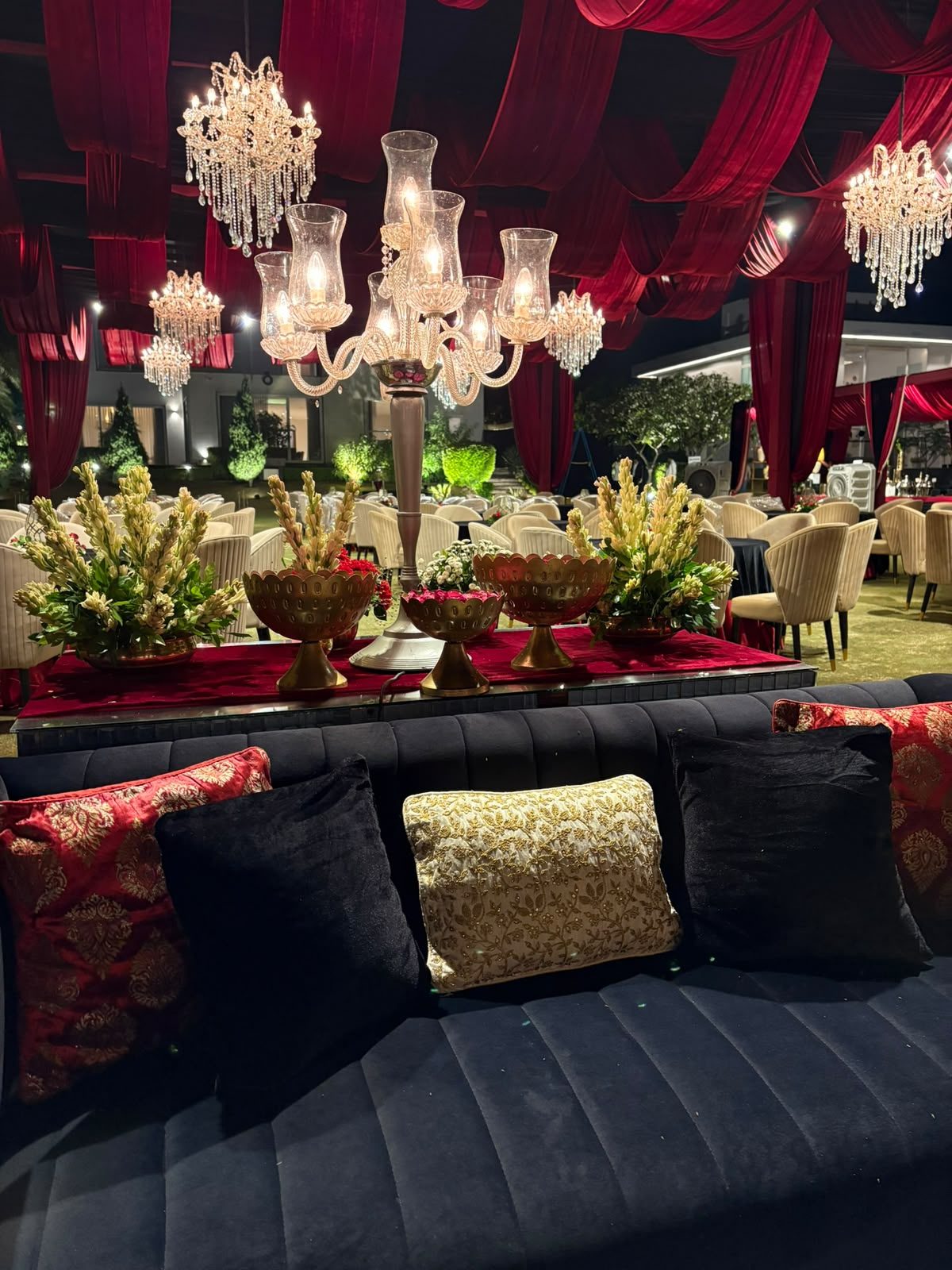 Lounge seating with red and gold cushions under crystal chandeliers
